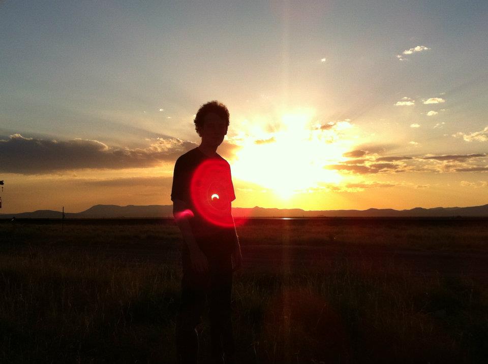 Silhouette of Allen against the sunset with the eclipsed sun as a lens flare