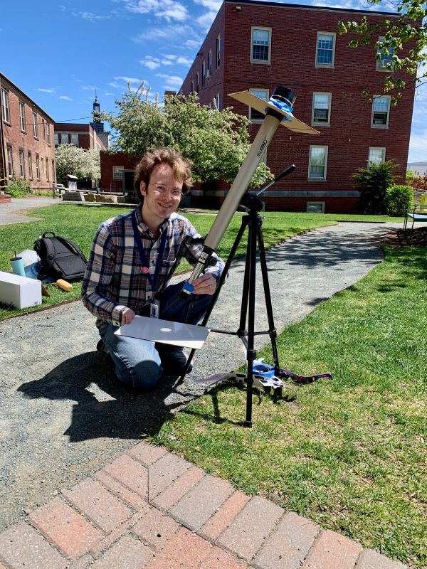Allen projecting an image of the sun with a telescope outdoors