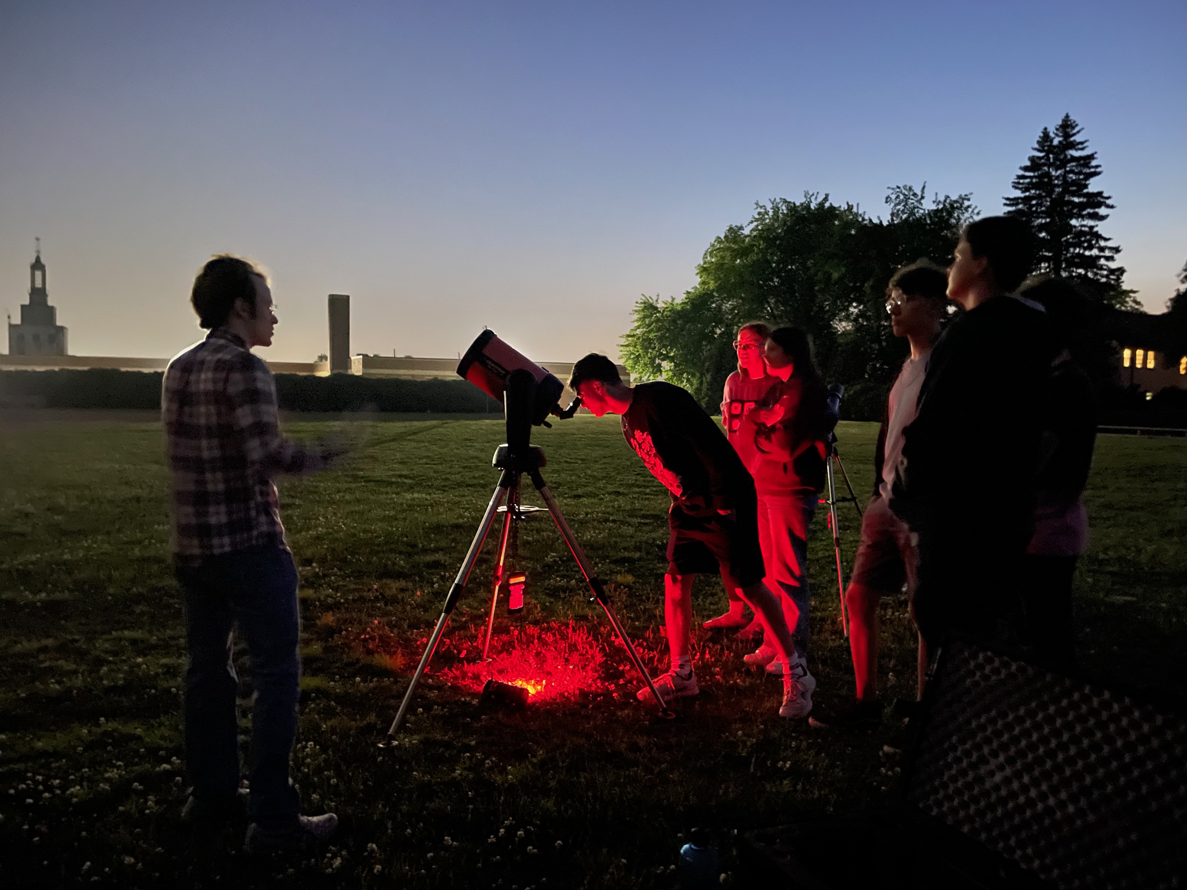 Astronomy club students observing at night with a telescope